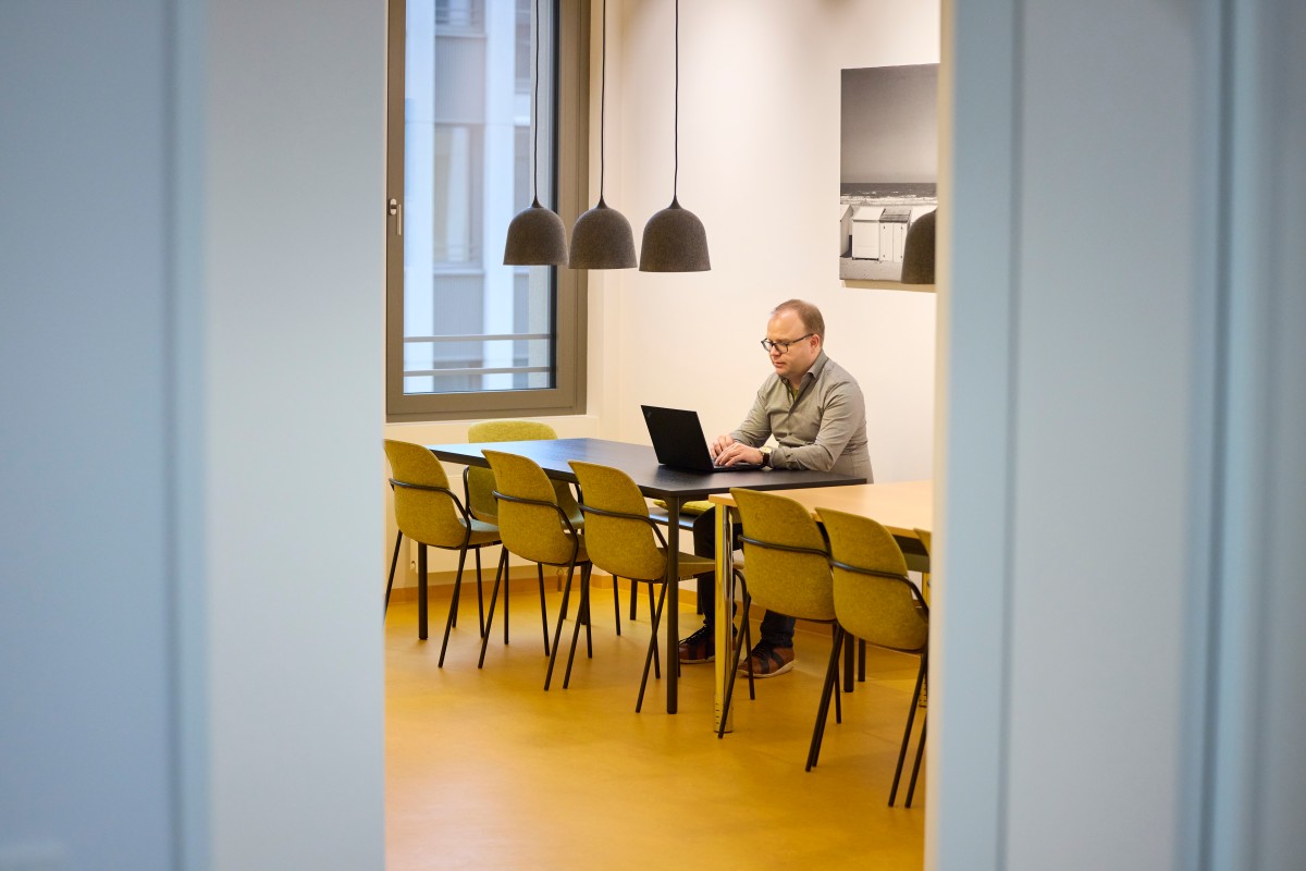 An IQWiG employee works on a laptop while sitting at a kitchen table