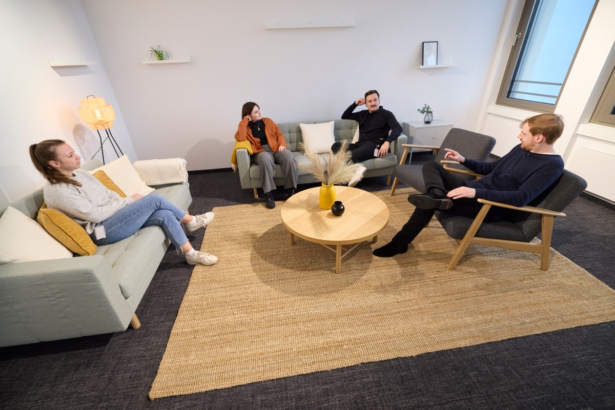 IQWiG employees sit in a living room seating area and chat