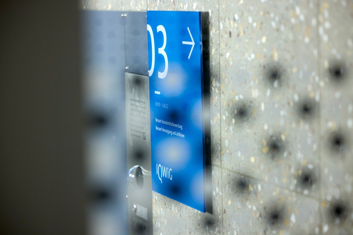Hinter einer Glastüre ein Blauer Wegweiser zur dritten Etage