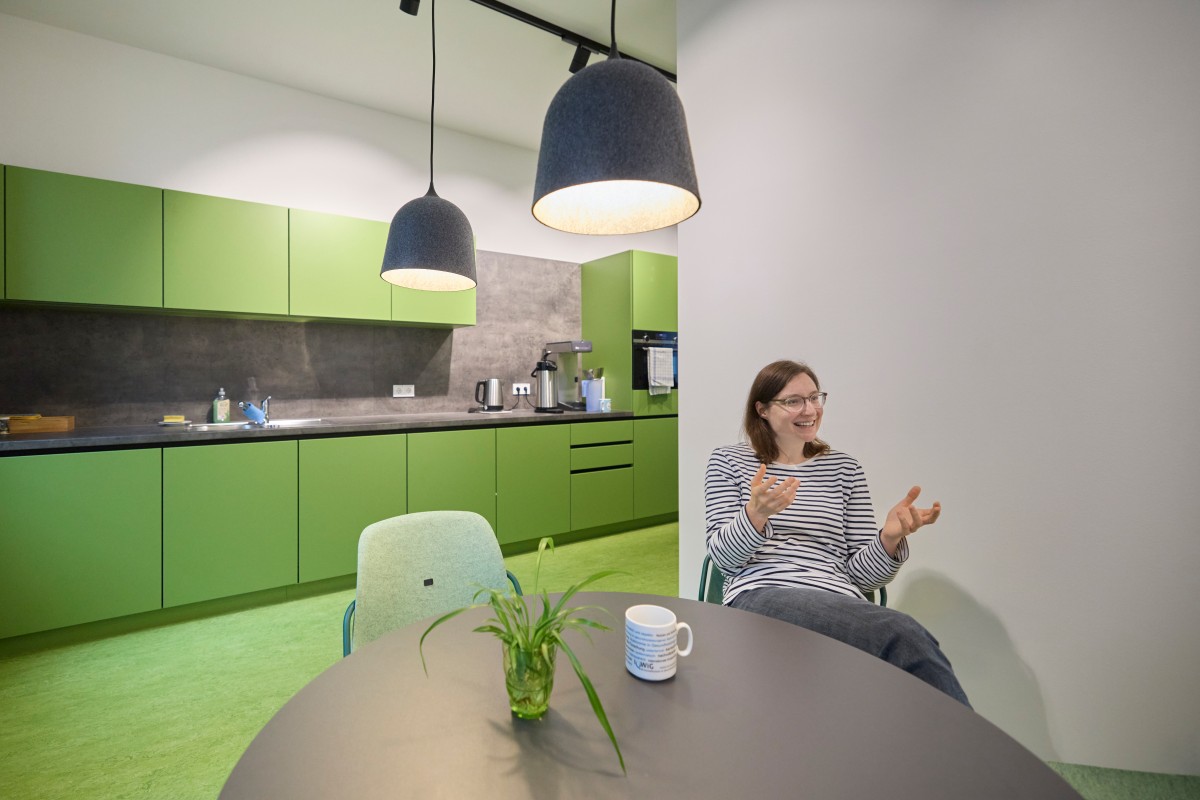 An IQWiG employee sits in a green kitchen during her break